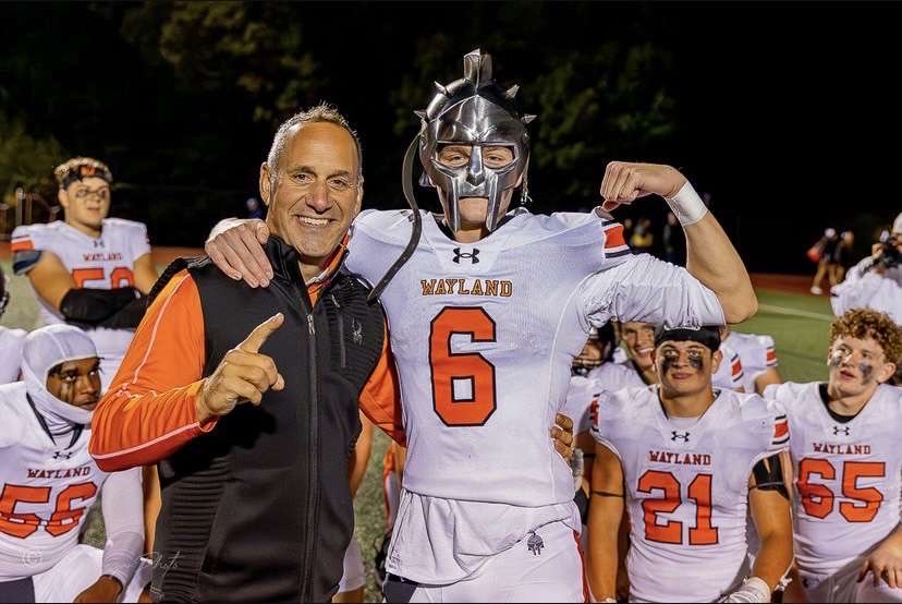 Keenan poses with the varsity football head coach, Scott Parseghian, after winning player of the game. The player of the game is awarded a gladiator helmet. 