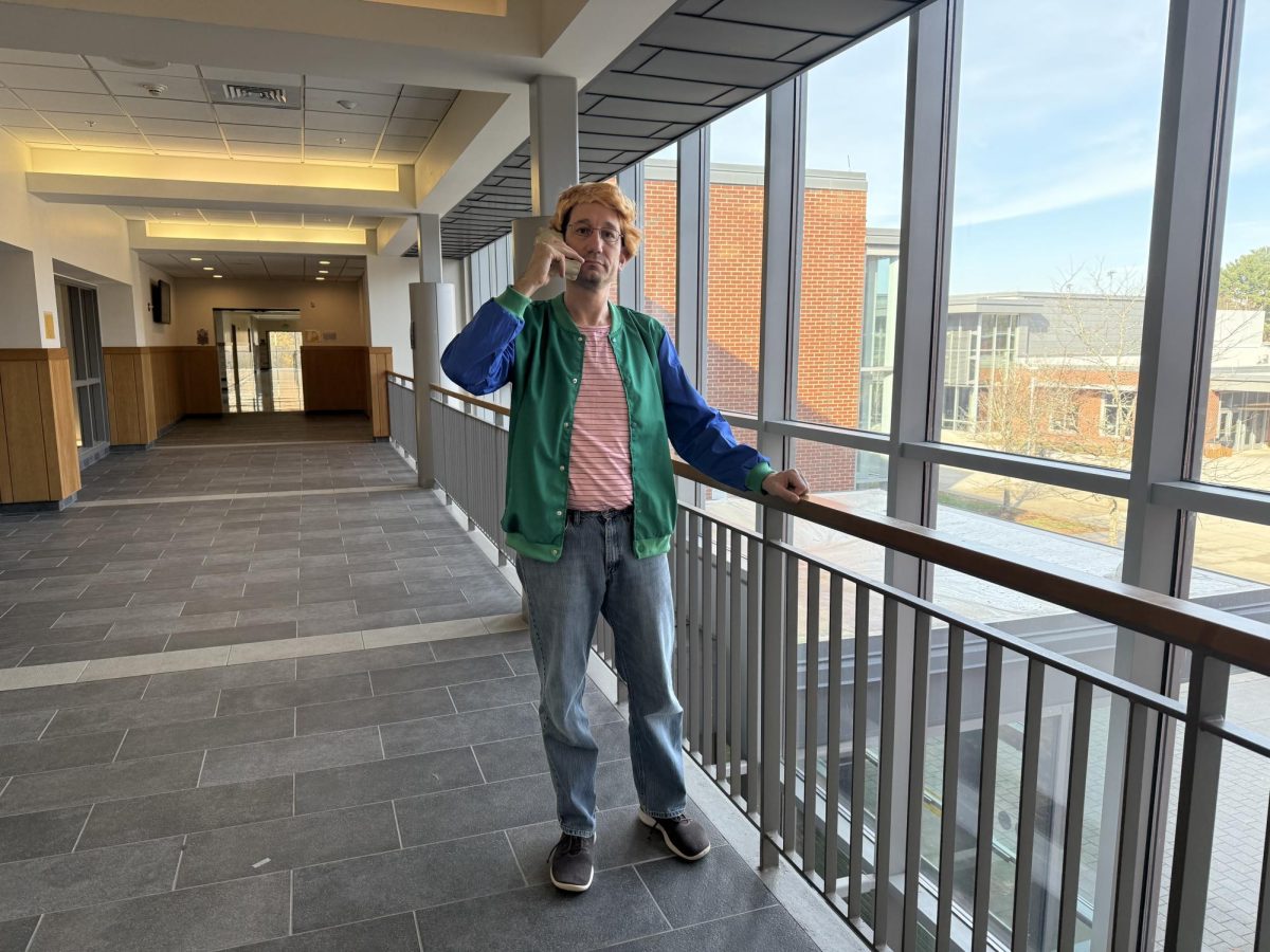 Taking a break from monitoring the hall, social studies department head David Schmirer poses for a photo. The history department dressed up as different decades, and Schmirer was Zack from a 90's show called "Saved By The Bell."