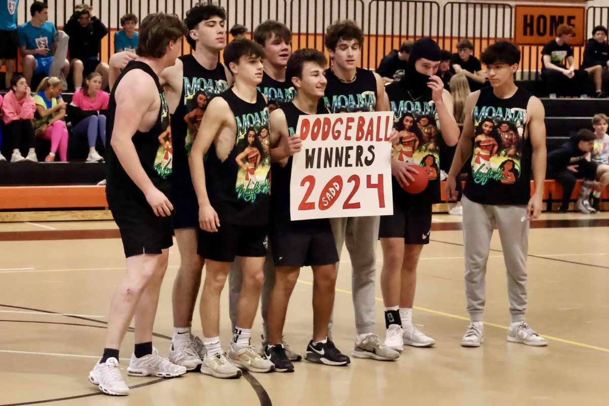 After a close match, a team of seniors stack together at the center of the basketball court to hold up the "Dodgeball Winners 2024" sign and take a picture.