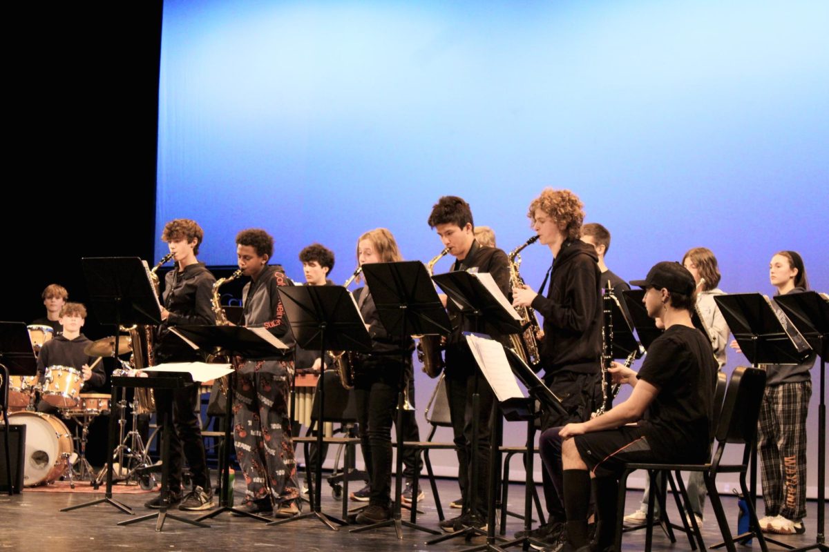 Five saxophone players stand up and take part in a saxophone solo.

wspn · Jazz Band (#3)