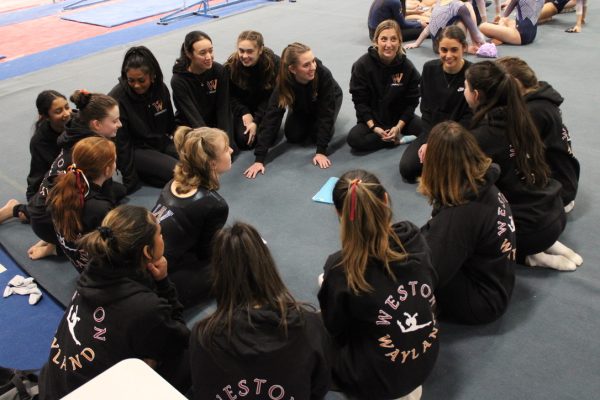 The Wayland-Weston gymnastics team huddles after their meet against Acton-Boxborough Regional High School while they wait for their placing. 