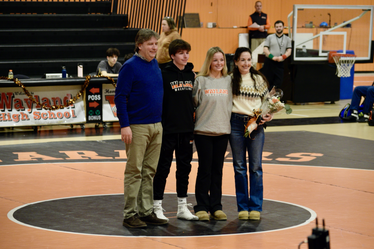 Senior captain Paul Lang and senior manager Amelia Lang are joined by their parents to take a photo for the wrestling team's senior night.  