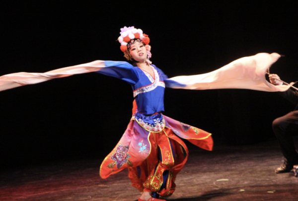 A dancer at the Lunar New Year celebration spins and dances to erhu music. The erhu is a traditional chinese instrument that uses a bow and two strings, and this involves the use of oversized flowing sleeves.