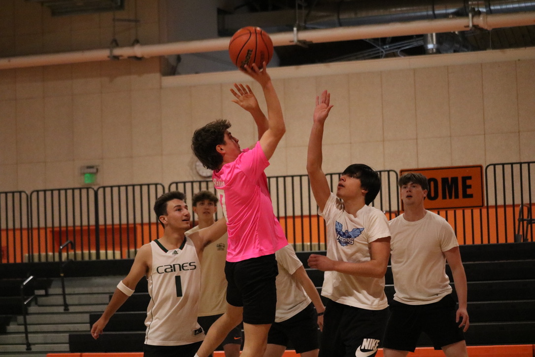 With many opposing players around him, senior Teddy Hage takes the ball up for a layup. White team players reached their arms up to block him, while pink team players watched from a far.