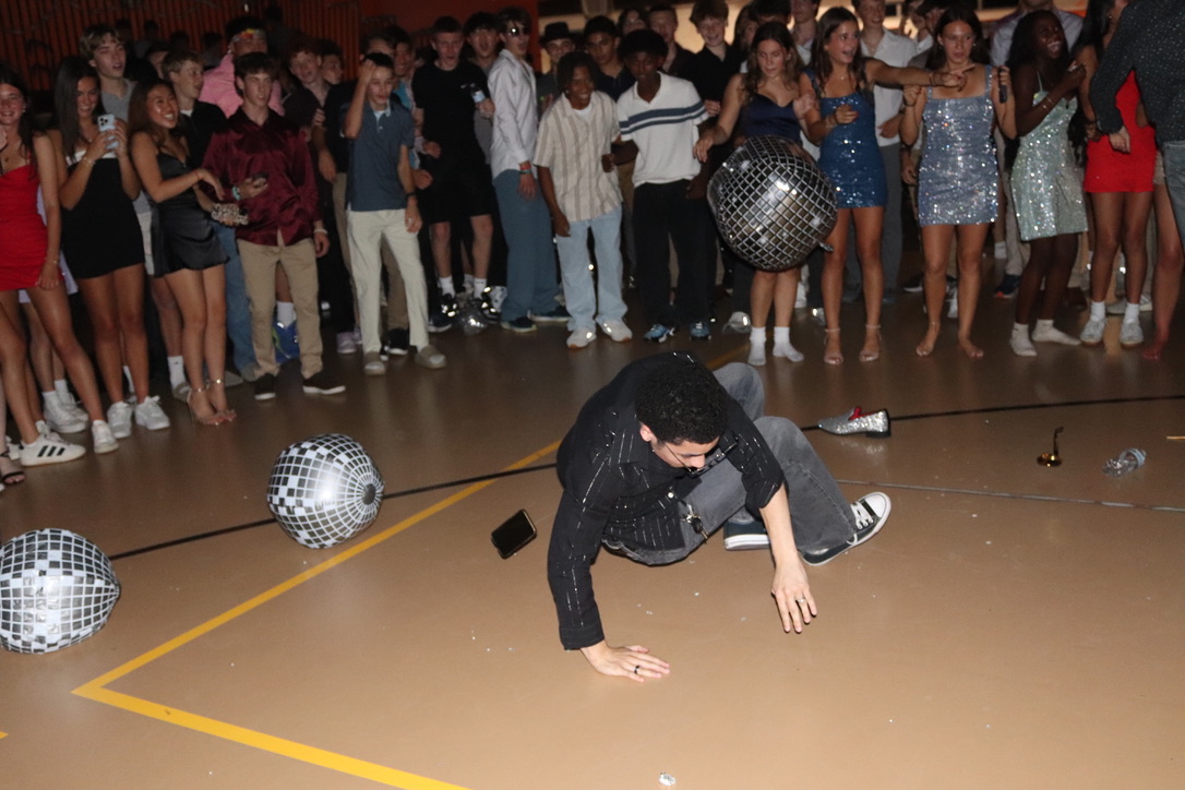 Students crowd around in a circle as junior Max Curbelo dances and spins on the floor.