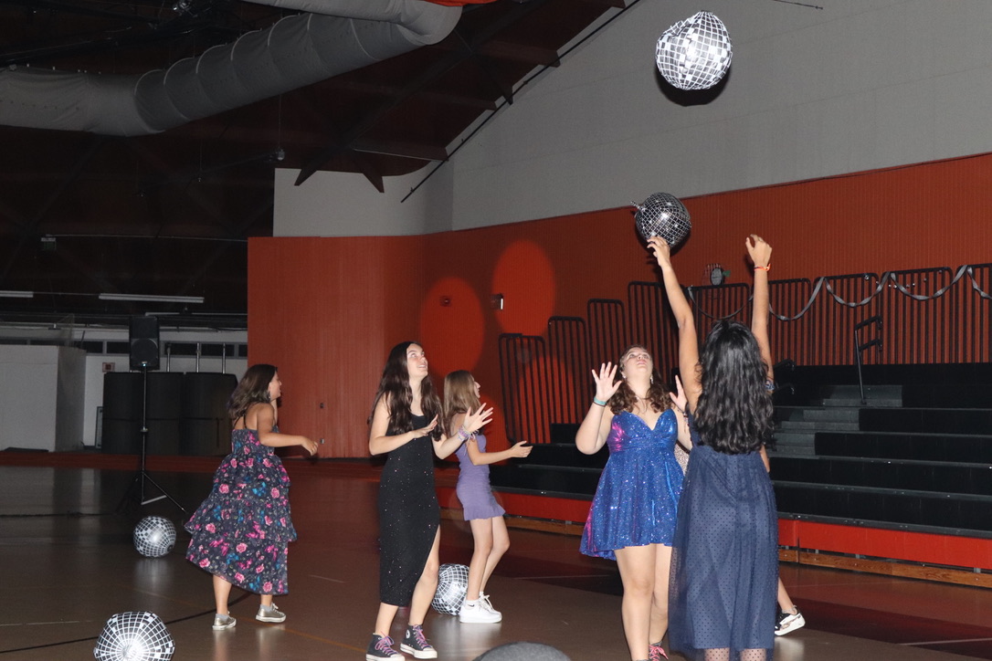 A group of students gather to toss up one of the many inflatable disco ball decorations that were scattered among the floor.