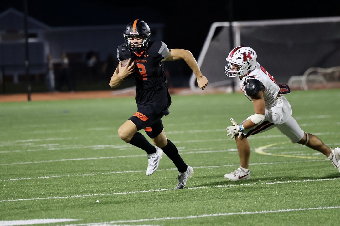 With a Holliston opponent at his side, junior Mikey Johansson looks to achieve a third down. Johansson is this year's starting quarterback. 
