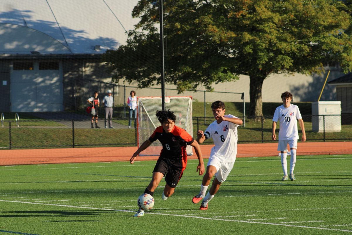 Running with the ball, senior Kane Chen beats a Natick defender to the ball, being in Natick's defensive zone.