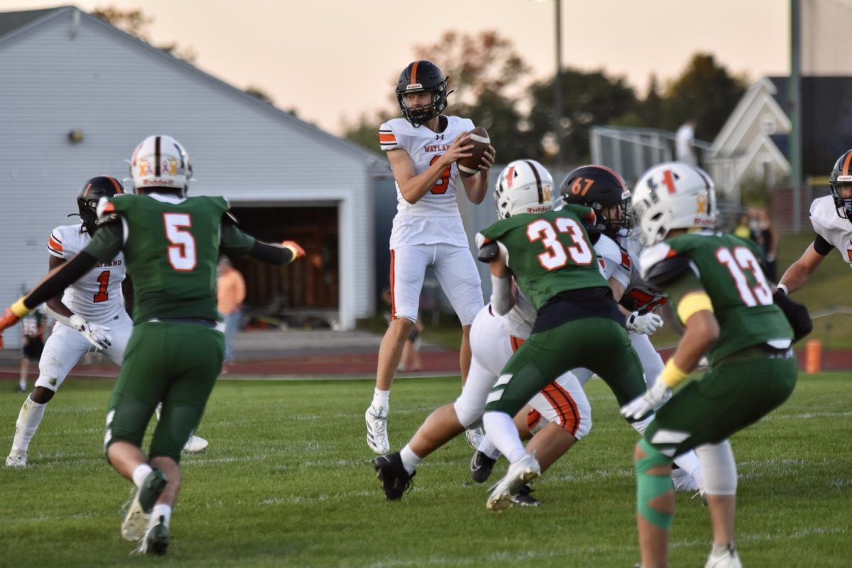 With a Hopkinton player sprinting towards him, junior quarterback Mikey Johansson looks to his right to hand off the ball to junior captain Brajae Walton. Along with having several successful throws, Johansson was able to achieve a touchdown in the final quarter.