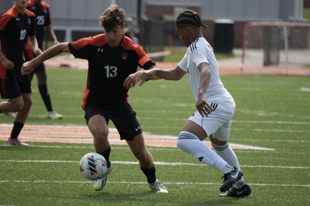 Senior captain Max Walsh fights with a Dearborn opponent for the ball, taking possession and dribbling it up the field.
