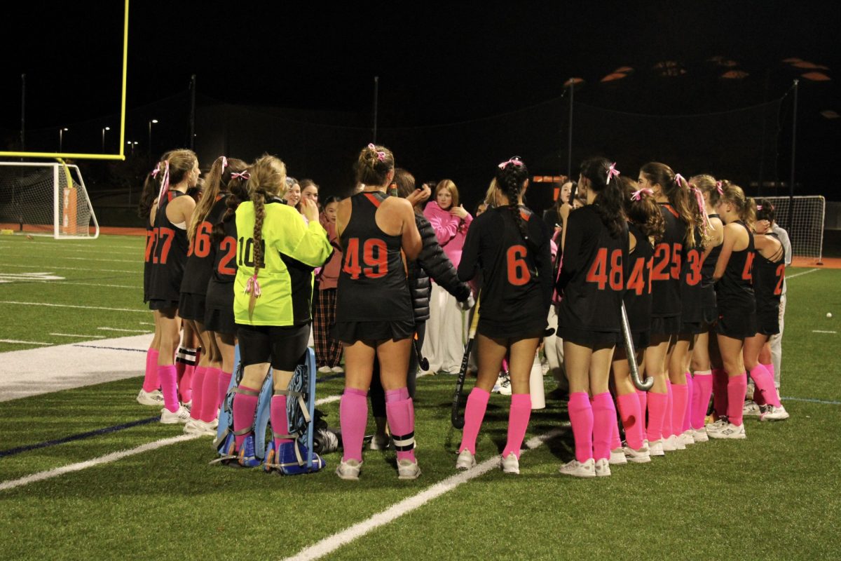 Following the match the field hockey team gathers around their coach as she overviews the game. 