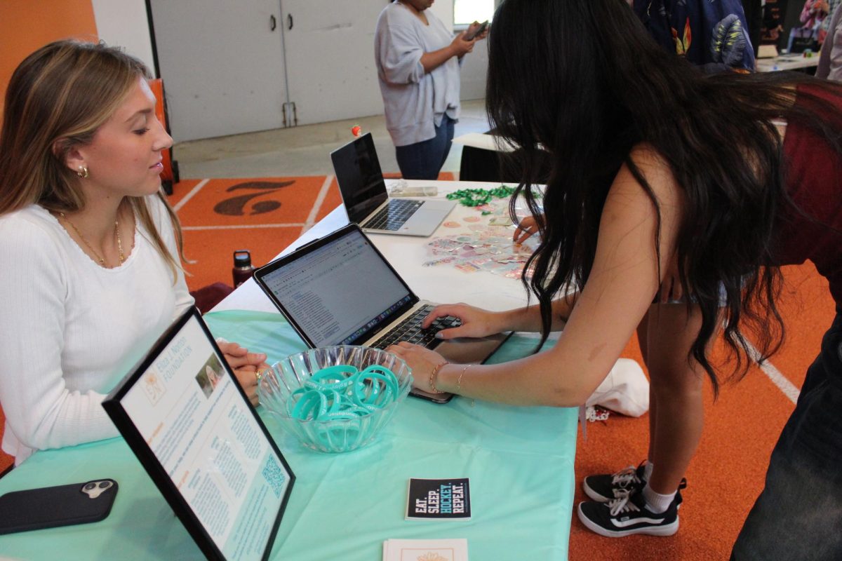 During the WHS club fair, senior Molly Bergeron is watching a student sign up for her club, Eliza J. Norton Foundation. In this club, students meet every week and come up with ideas to spread the message. "[This club] really touches a lot of people in the town," Bergeron said.