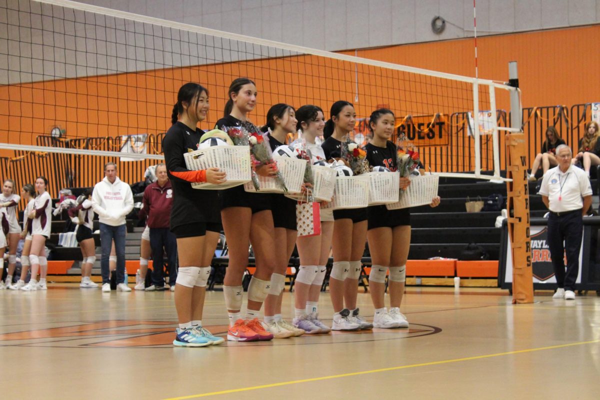 Seniors hold gift basket provided by juniors on the team. The baskets contained small gifts to congratulate the players on their senior night.