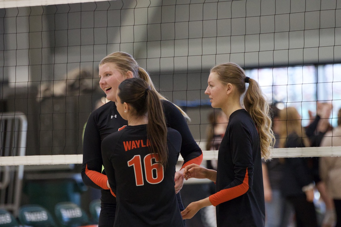 Setting up for the next set, sophomore Fiona Strehle, junior Anya Bayazitov and senior captian Anna Yalli join hands mid court. Joining hands shows support for one another during the game.