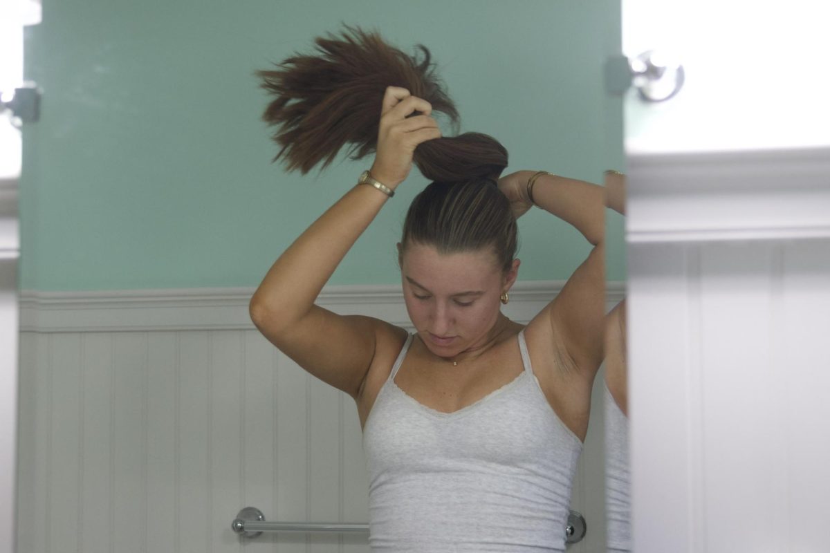 After waking up, getting ready to leave for her show, senior Annie Melander quickly throws her hair up in a low bun. 