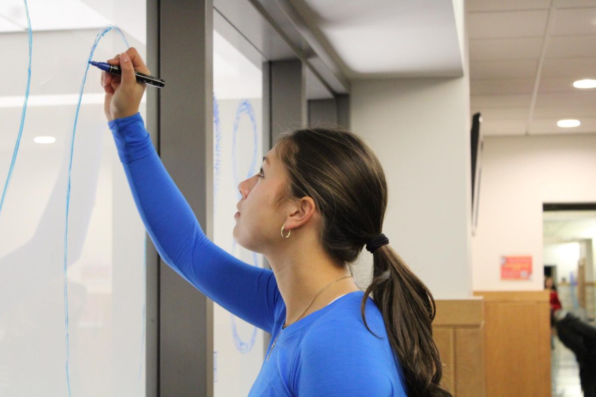Sophomore Izzy Irwin decorates the window with a marker, writing "2028," in reference to her class'd graduation year. Irwin serves on the Student Council, helping to plan Color Blast. "There was a lot of planning behind the scenes, like doing social media posts to make sure people knew to come and planning in advance," Irwin said.