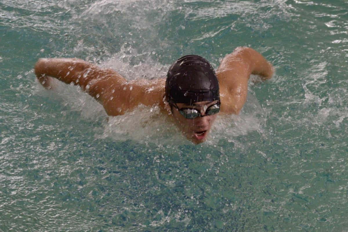 Sophomore Sebastian Guzman propels out of the water while swimming the 100 meter butterfly.