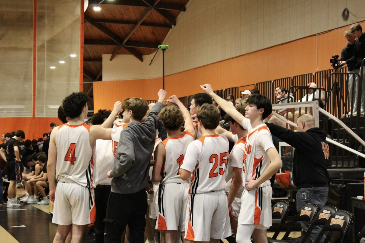 Fisting in the air, the boys varsity basketball team chants before the players go back onto the court.

