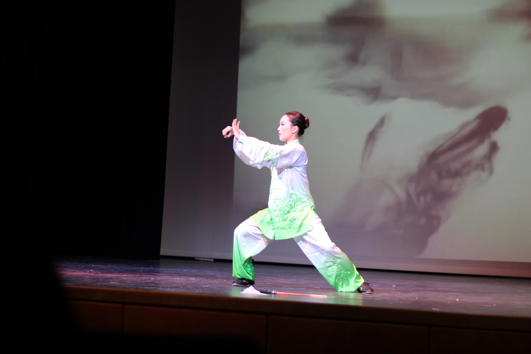 Performer Jasmine Wang places her sword on the ground as she transitions to different poses in a tai chi demonstration.