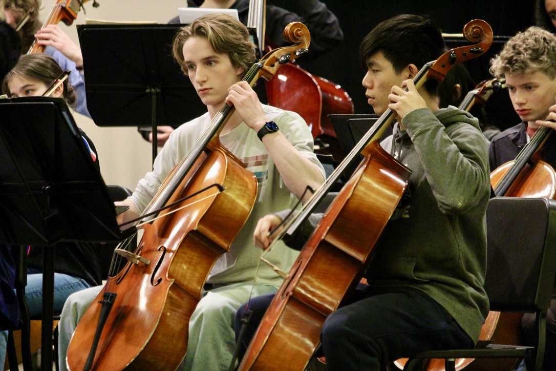 Seniors Ben Pyhtila and Alexander Lu focus as they perform their parts within the orchestra.