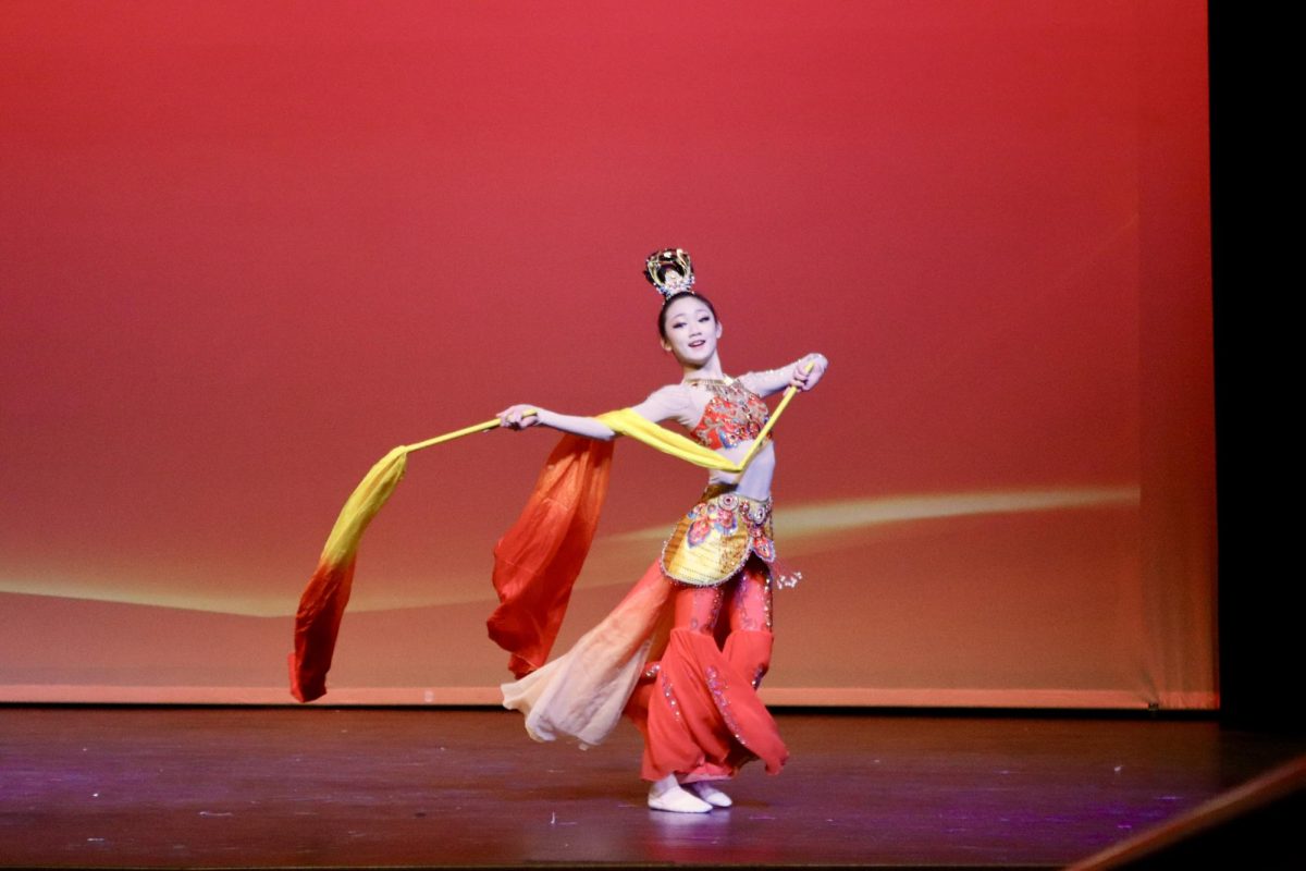 Artisan Dance Academy member Gemma Xu trails vibrant yellow and red fabrics behind her as she twirls during her performance of a traditionally inspired dance titled "Beneath the Eternal Moon."