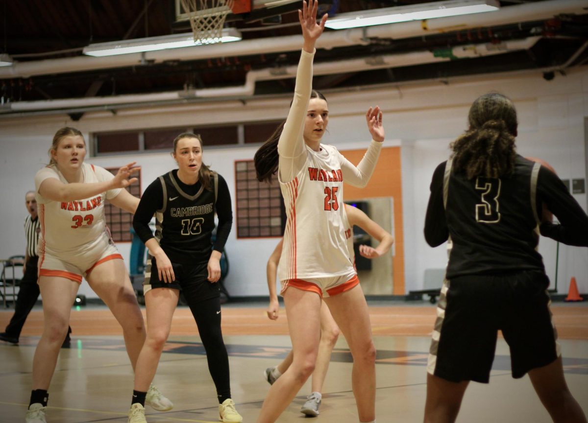 Raising her arms, sophomore Campbell Powers attempts to block a pass from a Cambridge player. This is Powers' second year on the girls varsity team.