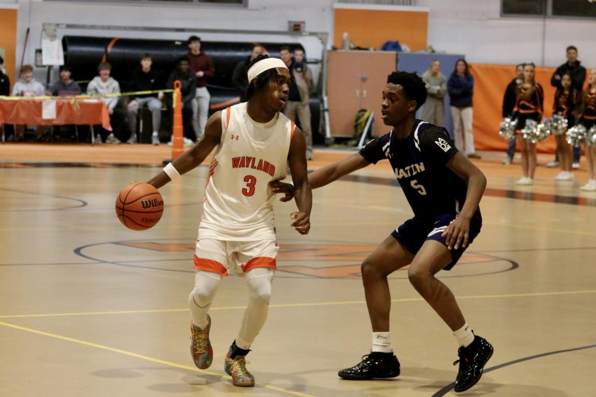 Dribbling around a Boston Latin defender, junior captain Josh Lewis-Guy moves the ball towards the net.