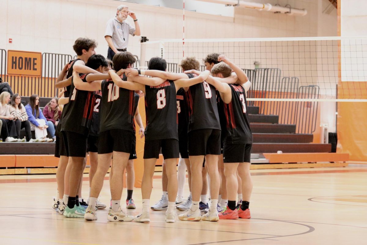 The starting players gather together on their side of the court.
