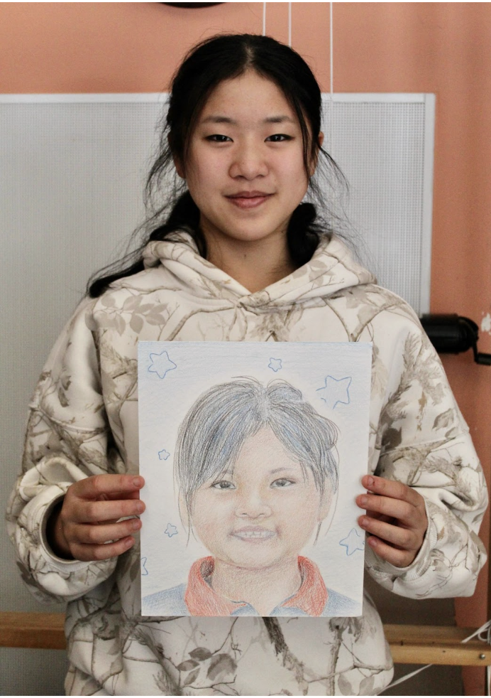  Wan holds her portrait that she drew for the Memory Project.