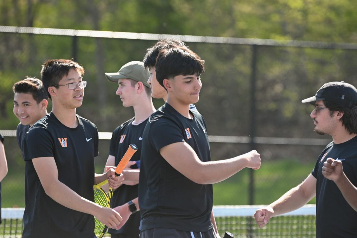 Sophomore Kiyoshi Niimi and junior Cesar Campos fist bump their other teammates as their names are being announced for their matches.