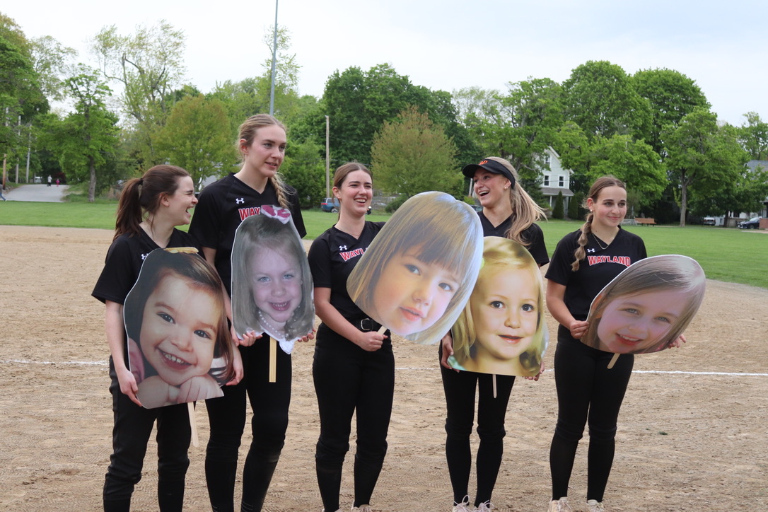 Laughing, (left to right) seniors Kiera Hines, Kelsey Kaufmann, Vivian Brevard, Sophia Beckett and Aubrey Calabro hold up pictures of them when they were little.