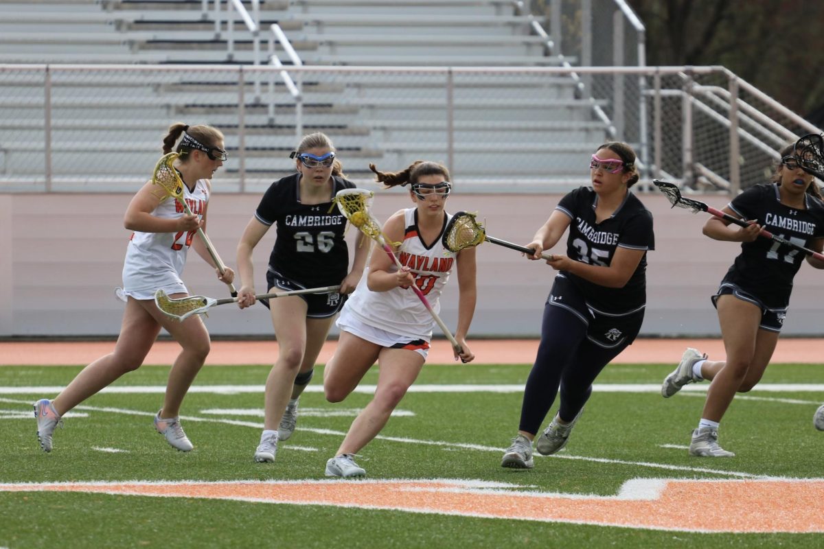 Junior Melina Antun runs through Cambridge Rindge and Latin School players, carrying the ball down line towards the opposing teams goal.