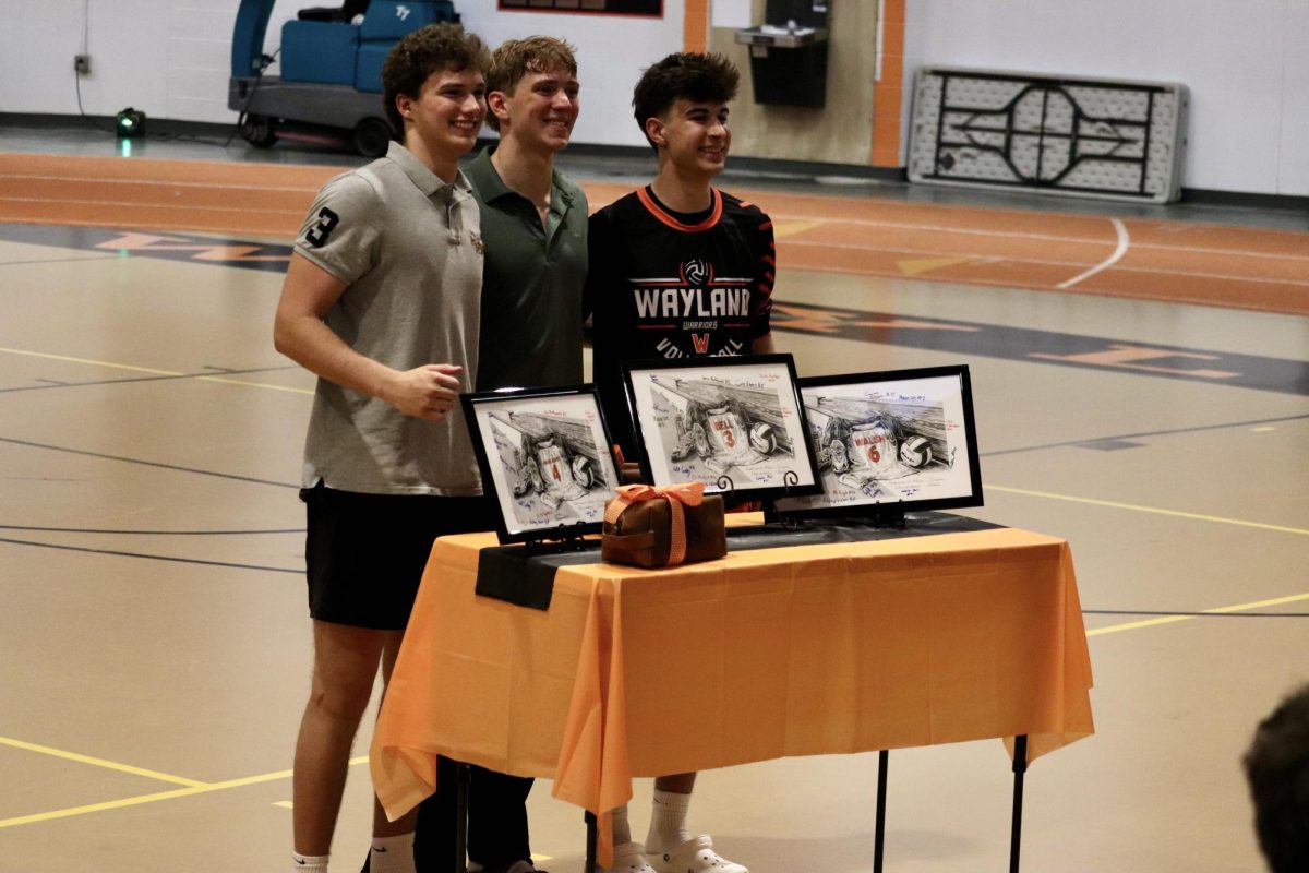 Following the ceremony, from left to right, senior captains Dylan Engelhardt, Finn Bell and senior Max Walsh smile, while receiving a gift. The painting features their jerseys and signatures from the entire team.