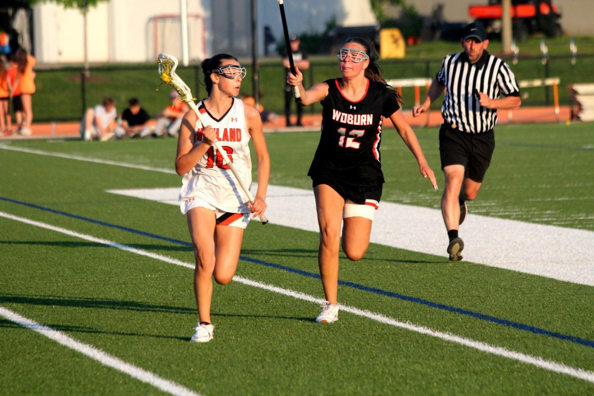 Freshman Ella Berenson runs down the sideline as a Woburn defender checks her. Berenson is one of four freshmen on the team.