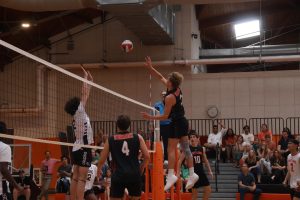 Senior Finn Bell leaps up and attempts a kill, contested by a Longmeadow defender.